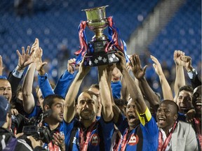 The Impact's Marco Di Vaio (left) and Patrice Bernier are surrounded by teammates after winning the Voyageurs Cup by beating Toronto FC 1-0 on June 4, 2014 at Montreal's Saputo Stadium.