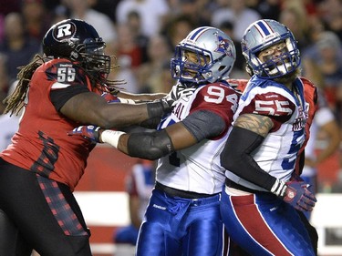 Montreal Alouettes' Michael Sam (94) and teammate Gabriel Knapton (55) battles with Ottawa Redblacks' SirVincent Rogers (55) during the first half of a CFL game in Ottawa on Friday, Aug. 7, 2015.