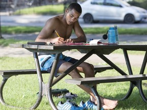 Marvin Hichem works at a picnic table in the shade in Jeanne Mance Park Aug. 17, 2015. The intense heat made him decide to work outdoors.