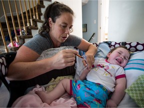 Ilyssa Shaffer uses a syringe to give her little daughter Ellie Fauteux a medicine she needs, on Saturday, Aug. 22, 2015. The 11-month Ellie Fauteux is affected by a rare genetic disease.