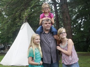 Stéphane Descheneaux poses for a photo with his three daughters, Marie-Lee, 11, left, Emmy, 8, top, and Audrey-Ann, 13, in front of a teepee outside the Abénaki Museum in Pierreville, a small town near Montreal.
