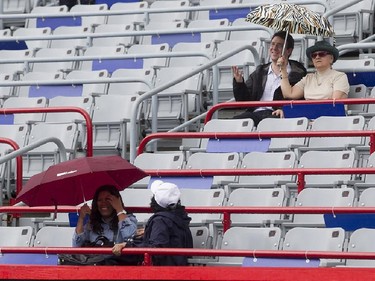Spectators shield themselves from the rain with umbrellas, prior to the Pablo Andujar and Kei Nishikori tennis match, during Rogers Cup tournament in Montreal on Wednesday August 12, 2015.