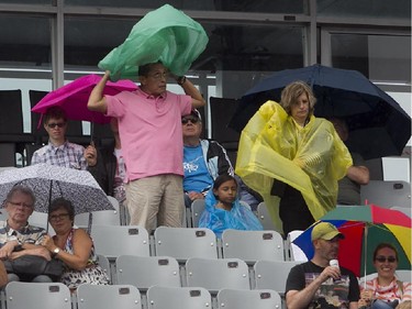 Spectators use umbrellas, and dawn rain gear prior to the Pablo Andujar and Kei Nishikori tennis match, during Rogers Cup tournament in Montreal on Wednesday August 12, 2015.