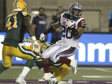 Montreal Alouettes Tyrell Sutton, right is tackled by Edmonton Eskimos Otha Foster and Odell Willis during Canadian Football League game in Montreal Thursday August 13, 2015.