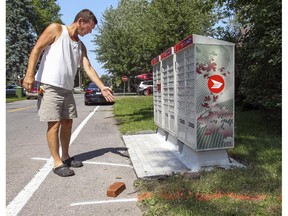 Hans Dybka shows how Canada Post's new community mailbox comes close to the circular driveway he plans to install in the front yard of the home on Strathmore Ave. Dorval. The white line on the pavement at his feet is his property line and the orange lines on his lawn mark where his driveway will be.