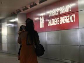 A woman carries a child as she leaves the Montreal Children's Hospital on Tuesday afternoon, Aug. 18, 2015.