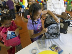 Kamille Mputu, 6, left and her sister Dedouce Mputu pack bags for school that they recieved at the Welcome Hall Mission in Montreal, Tuesday, Aug. 18, 2015.