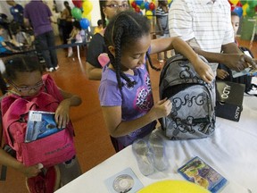 Kamille Mputu, 6, left and her sister Dedouce Mputu pack bags for school that they recieved at the Welcome Hall Mission in Montreal, Tuesday August 18, 2015.  They and their siblings are among more than 2,000 children who will get school supplies at the mission during an annual back-to-school programme in which clothes and school supplies are donated to kids in need.