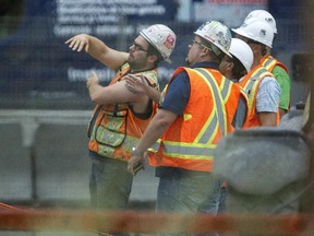 Workers gather underneath the Bonaventure Expressway at Mill Street where a worker fell Aug. 20, 2015.