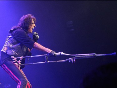 Alice Cooper holds a crutch on stage during a concert at the Bell Centre in Montreal, Monday August 24, 2015.