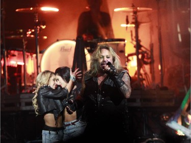 Lead singer Vince Neil from Mötley Crüe performs in concert  while two dancers hug each other at the Bell Centre in Montreal, Monday August 24, 2015.