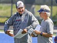 Alouettes head coach and general manager Jim Popp, right, listens to  quarterbacks coach Anthony Calvillo during practice in Montreal Monday, Aug. 24, 2015.