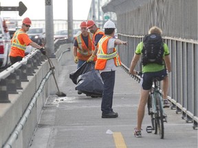Workers clean up blood and debris after a fatal collision between two cyclists on the Jacques-Cartier Bridge  bike path in Montreal, Monday, Aug. 24, 2015.