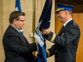 Montreal Mayor Denis Coderre, left, hands a flag of the Service de police de la Ville de Montreal (SPVM) to its new police chief Philippe Pichet, right, during his swearing in ceremony at Montreal City Hall on Friday, August 28, 2015.