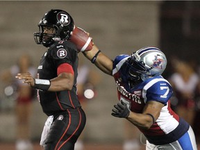 The Alouettes' John Bowman hits Ottawa Red Blacks quarterback Henry Burris's arm as he attempts a pass during CFL game at Montreal's Molson Stadium on Aug. 29, 2014.