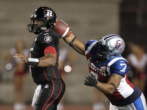 MONTREAL, QUE.: AUGUST 29, 2014 -- Montreal Alouettes John Bowman, right, hits Ottawa Red Blacks quarterback Henry Burris's arm as he attempts a pass during Canadian Football League game in Montreal Friday August 29, 2014. (John Mahoney  / THE GAZETTE) ORG XMIT: 50793-10282