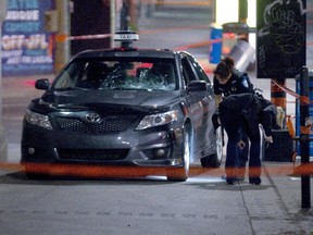 Police officers examine a taxi cab which was used to hit two pedestrians at the intersection of Ontario and St Laurent Blvd. on Aug. 3, 2015.
