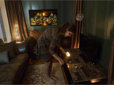 Anna Delfino lights a candle in a rain-forest themed living room in her apartment in Montreal, which features greens, bronzes and browns as well as some items from Thailand. She shares her 2-bedroom apartment with a former schoolmate.