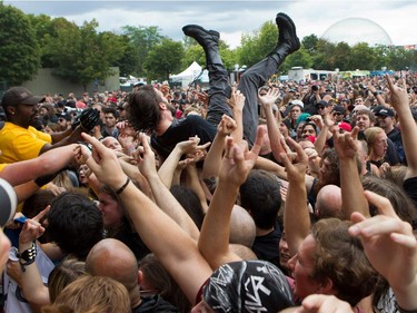 A fan body surfs his way to the pit at the front of the stage as Arch Enemy performs at Heavy Metal Montreal at Parc Jean-Drapeau in Montreal on Friday August 7, 2015.