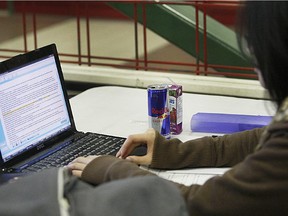 A student works on her computer with a juice and  an energy drink nearby.