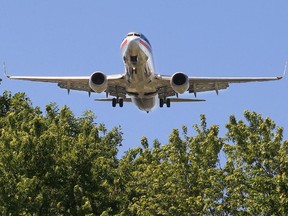 An American Airlines jet flies over trees near the intersection of Graham and Goldfinch Aves. in Dorval on its final approach to Pierre Elliot Trudeau Airport.