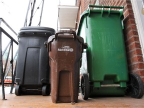 A compost container sits between a garbage can, left, and a recycling bin on the balcony of a house in the Rosemont—La Petite-Patrie borough.