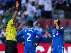 Montreal Impact's Victor Cabrera, right, is shown a red card by referee Silviu Petrescu as teammate Ambroise Oyongo (2) watches after a tackle on Vancouver Whitecaps' Octavio Rivero during first half Canadian Championship final soccer action in Vancouver on Aug. 26, 2015.