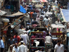 Indian commuters travel through a market area of New Delhi on the eve of World Population Day.