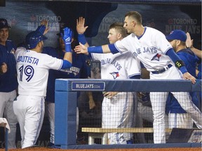 The Blue Jays' Jose Bautista is congratulated by teammates in the dugout after hitting a solo home run against the Oakland Athletics at Toronto's Rogers Centre on Aug. 11, 2015.
