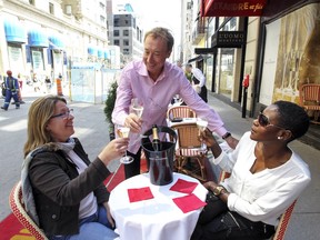 Chez Alexandre owner Alain Creton talks with customers Adja Ba, right, and Dominic Valois on the terrasse of his restaurant on Peel St. in Montreal Wednesday May 06, 2015.