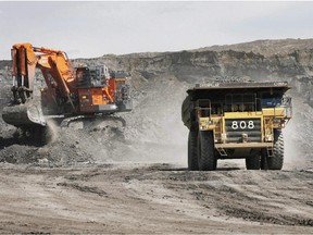 A haul truck carrying a full load drives away from a mining shovel at the Shell Albian Sands oilsands mine near Fort McMurray, Alta.