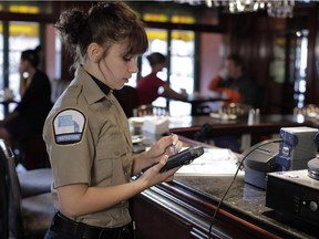 A Revenue Quebec inspector poses with an "all sales revenue module" at a restaurant.