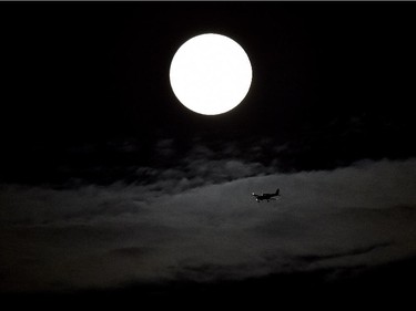 A small airplane flies with the supermoon behind as it begins to rise in Mississauga, Ont., on Sunday, Sept. 27, 2015.