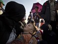 A Syrian child sleeps on his mother's lap as they wait with others to board a bus that will take them to the center for asylum seekers, after crossing the Serbian-Hungarian border near Roszke, southern Hungary,Sunday, Sept. 13, 2015.