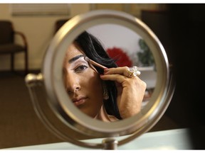 In this photo taken June 6, 2015, Andii Viveros, 21, of Davie, Fla., applies makeup as she prepares to host the annual Sun Serve LGBTQA Colors of the Wind youth prom in Fort Lauderdale, Fla. Viveros, who identifies as a transgender female, said she was always different from an early age growing up as a boy. Her parents accepted her to be anyway she wanted to be. She fought for her rights in high school, sometimes violating the school's code of conduct by wearing dresses. She was elected prom queen in high school and is now studying sociology in college.