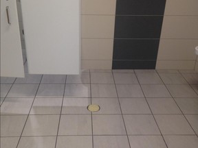 A taped-over drain in the men's bathroom of the new Montreal Children's Hospital in the lobby near the back atrium in the middle of August 2015. The bathroom is one of several locations at the Children's where sewer water has backed up.