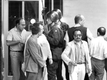 A heavily armed police officer watches people leaving the Hall building after teacher Valery Fabrikant's deadly shooting spree on August 24, 1992.