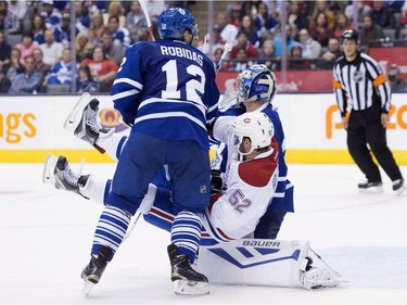 Montreal Canadiens' Bud Holloway, centre, is tripped by Toronto Maple Leafs defenceman Stephane Robidas, left, goaltender James Reimer during third period pre-season exhibition NHL hockey action in Toronto on Saturday, September 26, 2015.