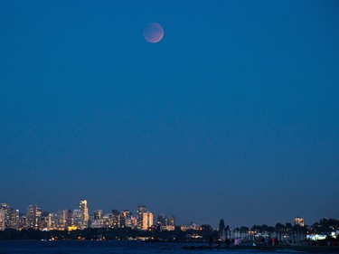 The moon rises over downtown buildings during a "supermoon" eclipse in Vancouver, B.C., on Sunday, Sept. 27, 2015.