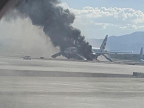 In this photo taken from the view of a plane window, smoke billows out from a plane that caught fire at McCarren International Airport, Tuesday, Sept. 8, 2015, in Las Vegas. An engine on the British Airways plane caught fire before takeoff, forcing passengers to escape on emergency slides.