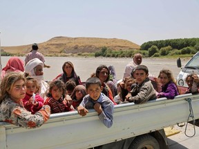 In this Sunday, Aug. 10, 2014, displaced Iraqis from the Yazidi community cross the Iraq-Syria border at Feeshkhabour bridge over Tigris River at Feeshkhabour border point, northern Iraq.