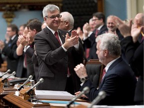 Quebec Minister responsible for Canadian Intergovernmental Affairs Jean-Marc Fournier, left, is joined by government members as they applaud Quebec Premier Philippe Couillard, right, after responding to second opposition questions Wednesday, November 19, 2014 at the legislature in Quebec City.