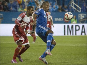 Montreal Impact's Didier Drogba keeps the ball from New England Revolution's Jeremy Hall during first half MLS action in Montreal on Saturday, September 19, 2015