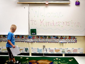 A kindergarten student inspects an alphabet display in his first day of school.