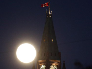 The supermoon is shown low on the horizon behind the Peace Tower on Parliament Hill in Ottawa on Sunday, Sept. 27, 2015.
