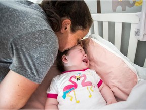 Ilyssa Shaffer kisses her little daughter Ellie Fauteux in her crib at the Fauteux family's house in Vaudreuil. The baby girl is affected by a rare genetic disease.