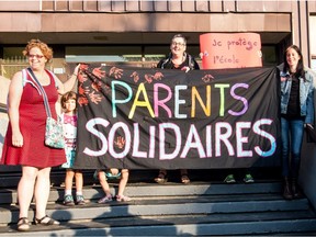 From left to right: Sophie Crepeau, Estelle Guérin (kid), Anna Kruzynski and Fanny Perret hold a banner in front of École Charles-Lemoyne, on Tuesday September 1, 2015, in Montreal, Quebec. Parents and teachers joined in  a common protest against school budget cuts.