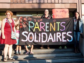 From left to right: Sophie Crepeau, Estelle Guérin (kid), Anna Kruzynski and Fanny Perret hold a banner in front of École Charles-Lemoyne, on Tuesday September 1, 2015, in Montreal, Quebec. Parents and teachers joined in  a common protest against school budget cuts.