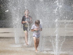 Charlie Edinson and Oscar Cam,let (rear) run through the water fountian to cool off in Westmount Park in Westmount near Montreal, Monday August 30, 2010. The city of Montreal has closed the public pools just as a late summer heat wave has hit the city.