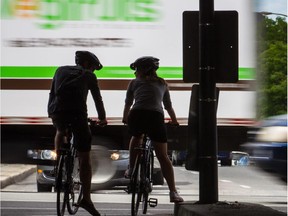 Cyclists wait on a cycling path under the Highway 40.